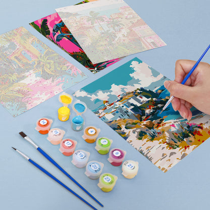 Artistic painting activity with colorful paint samples and brushes on a blue surface. Mini Painted Journeys 6 Pack Paint by Numbers