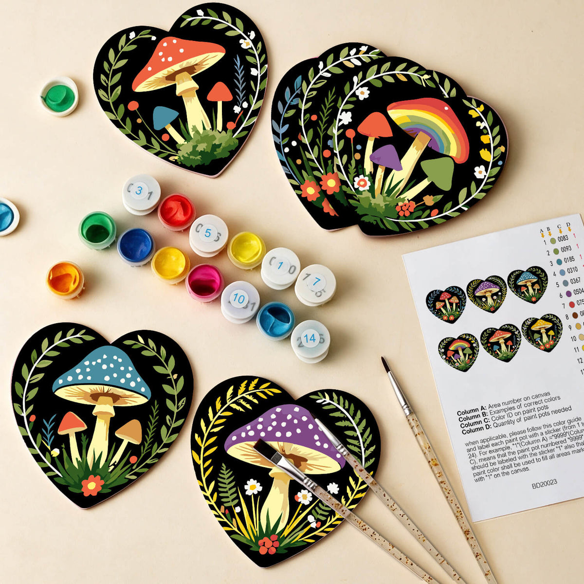Four heart-shaped wooden coasters with hand-painted colorful mushroom designs are arranged on a light beige background with paint pots, paintbrushes, and a color chart sheet. Enchanted Mushrooms Coasters - 6 Pack Paint by Numbers Package