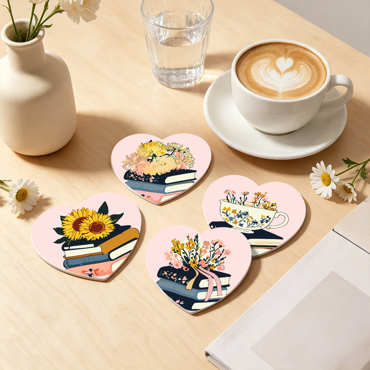 Four heart-shaped coasters with floral and book illustrations arranged on a light wood table next to a cup of latte, a small vase, and daisies. Floral Blossoms Coasters - 6 Pack Paint by Numbers Lifestyle