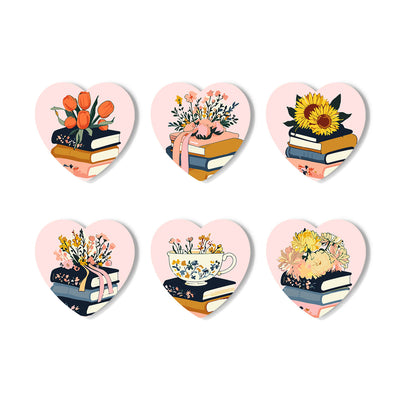 Six heart-shaped decorative stickers arranged in two rows on a white background. Each heart contains a pastel illustration with stacked books, flowers, a pink ribbon, a teacup, and a bird. Floral Blossoms Coasters - 6 Pack Paint by Numbers