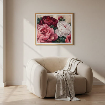 Beige armchair with a blanket next to a floral painting on a wall.
