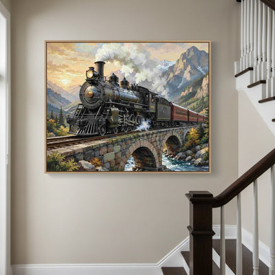 A framed canvas print of a vintage steam locomotive traveling over a stone bridge with mountains in the background, displayed on a beige wall in a staircase hallway. Steam Locomotive Canvas - Paint by numbers lifestyle