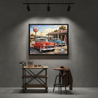 Framed painting of a vintage gas station scene with classic cars on a gray wall.
