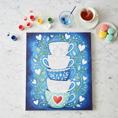 paint by numbers with a stack of teacups on a blue background, surrounded by coloring supplies.